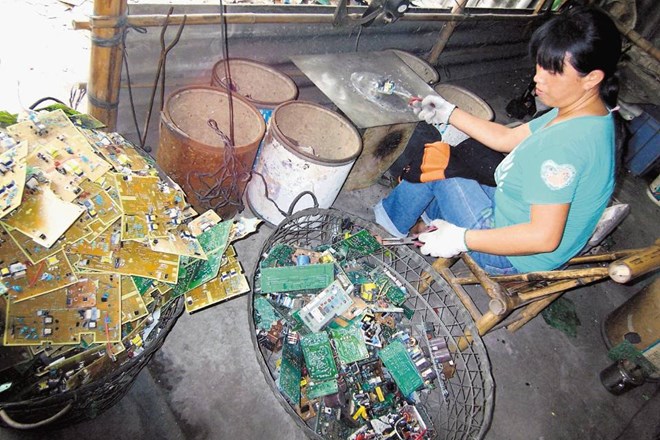 Delavka v obratu v kitajskem mestu Guiyu razstavlja dele računalnika. 