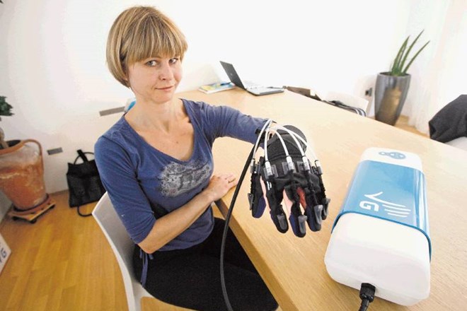Fizioterapevtka Tatjana Jeglič z robotsko roko za trening prizadete roke po možganski kapi. 