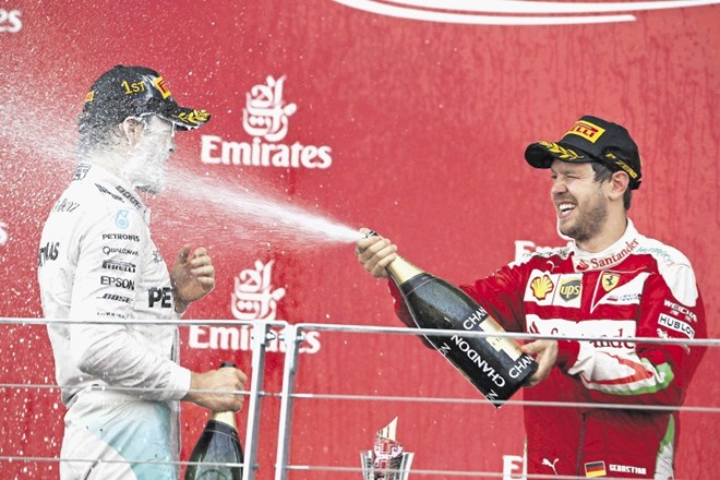 Drugouvrščeni Sebastian Vettel (desno, Ferrari) je zmagovalca rojaka Nica Rosberga (Mercedes) na zmagovalnem odru zalil s...