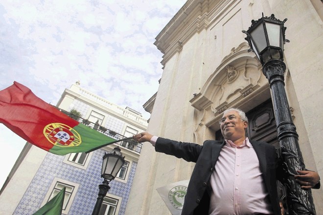 Razposajeni portugalski  premier Antonio Costa maha z državno zastavo. S svojimi dosežki je za zdaj lahko zadovoljen.
