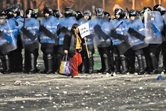 Protestnik v Bukarešti hodi pred kordonom policistov z napisom: »Vsak dan bomo tukaj.«