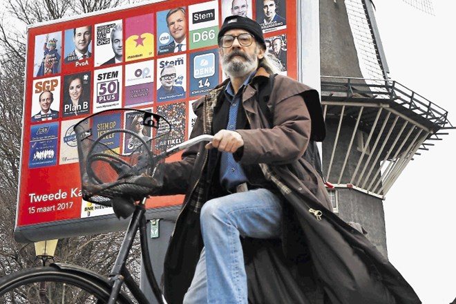 Amsterdamčan  se pelje mimo mlina, polepljenega s predvolilnimi plakati. Analize kažejo, da številni državljani  tik pred...