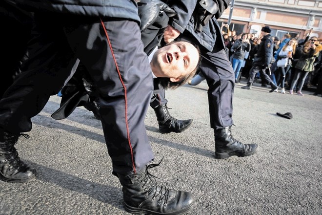 Policisti odnašajo aretiranega moškega s protestov v Moskvi.