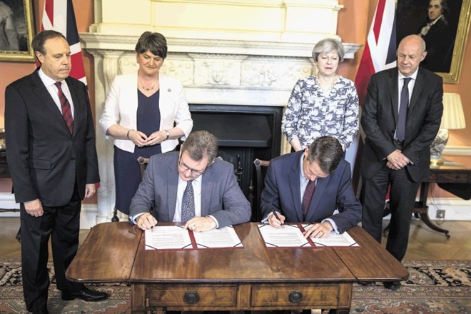 Premierka Mayeva in voditeljica stranke DUP Fosterjeva nadzirata podpis sporazuma, ki je vladi prinesel večino.