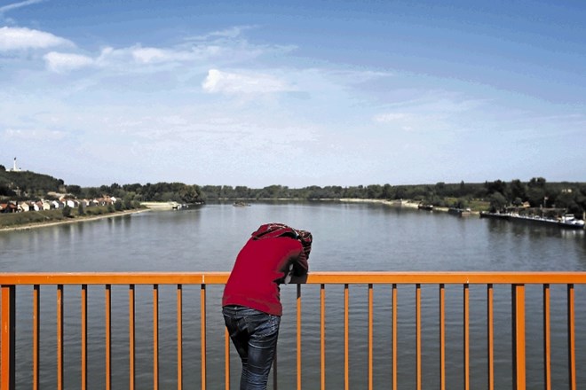 Ženska gleda z mostu čez Donavo, ki povezuje Srbijo in Hrvaško. Meja na reki je sporna, zdaj se začenjajo novi poskusi, da bi...