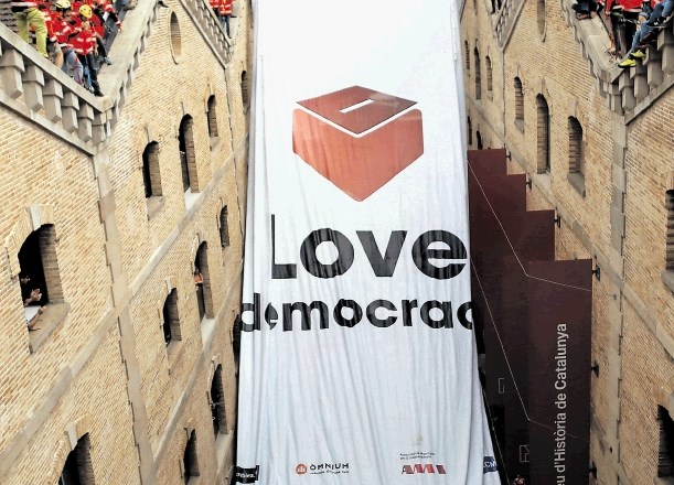 Gasilci na poslopju muzeja katalonske zgodovine v Barceloni razvijajo veliko zastavo v podporo referendumu o neodvisnosti.