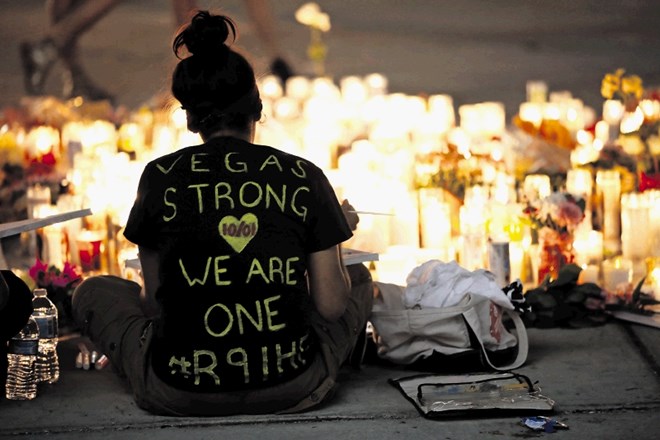 Ženska sedi ob svečah in cvetju v Las Vegasu, kjer je strelec v nedeljo ubil najmanj 59 ljudi.