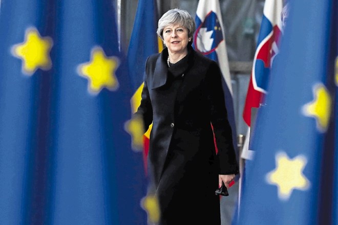 Britanska premierka prihaja na sestanek v Bruslju mimo zastav EU in njenih članic.