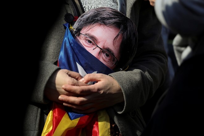 Protestnik drži v rokah masko s podobo Puigdemonta med današnjimi demonstracijami v podporo kandidatu za voditelja Katalonije...