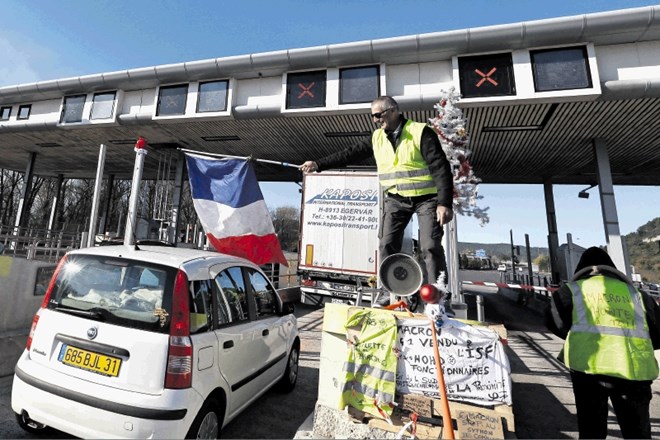 Protestnik v rumenem telovniku pred cestninsko postajo pri Aix-en-Provence na jugovzhodu države maha z zastavo po zmagi nad...
