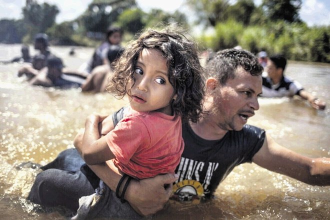 Reutersov fotograf Adrees Latif je oktobra lani v objektiv ujel Hondurašana Luisa Acosto, ki petletnemu Angelu Jesusu pomaga...