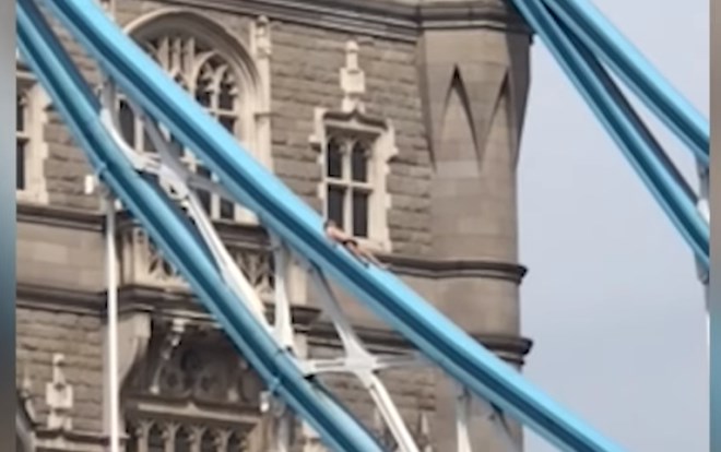 #video Na pol nag se je sončil na vrhu londonskega Tower Bridga in ustavil promet