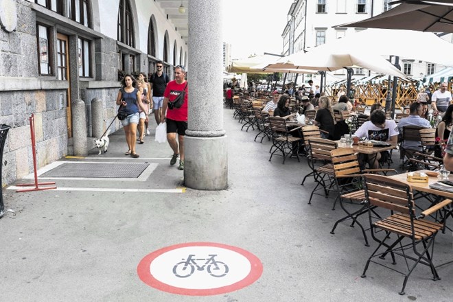 Kolesarje sveže talne oznake obveščajo, da je kolesarjenje pod Plečnikovimi arkadami prepovedano.