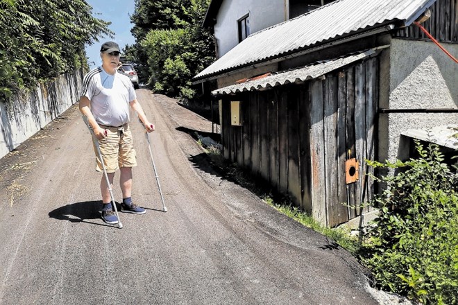 Marijan Jelen na asfaltirani občinski cesti, ki mu preprečuje vstop v hišo.