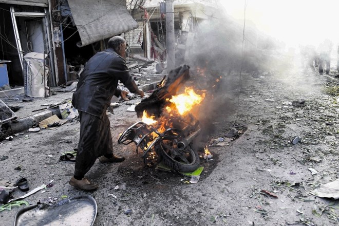 Moški gasi motor na prizorišču eksplozije avtomobila bombe  v mestu Tel Abjad na severu Sirije, v kateri je bilo ubitih...