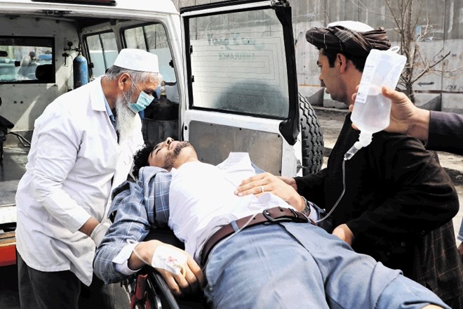 Zdravnik pomaga pri prevozu ranjenega v napadu Islamske države v Kabulu.