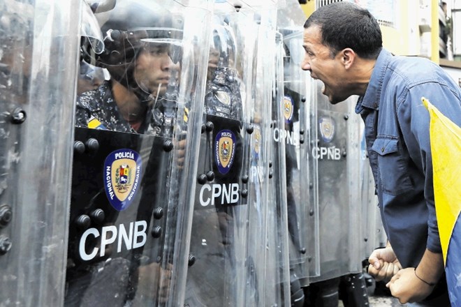 Protestnik vpije na policiste, ki so spremljali shod opozicije v  Caracasu.
