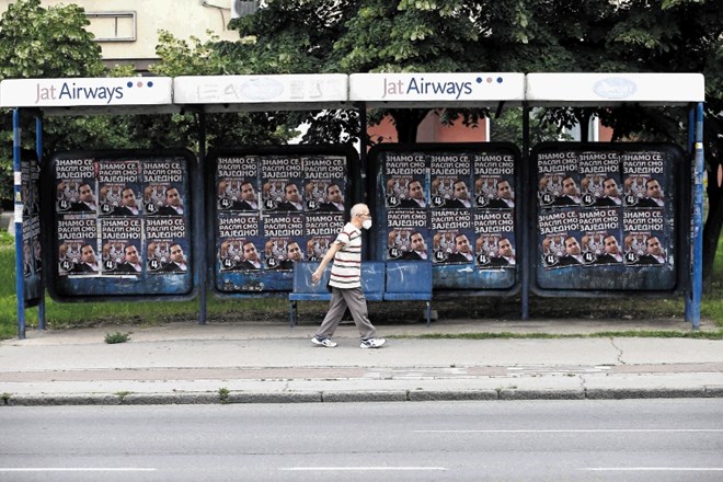 Moški hodi mimo niza predvolilnih plakatov v Beogradu. Srbi gredo na volitve v nedeljo.