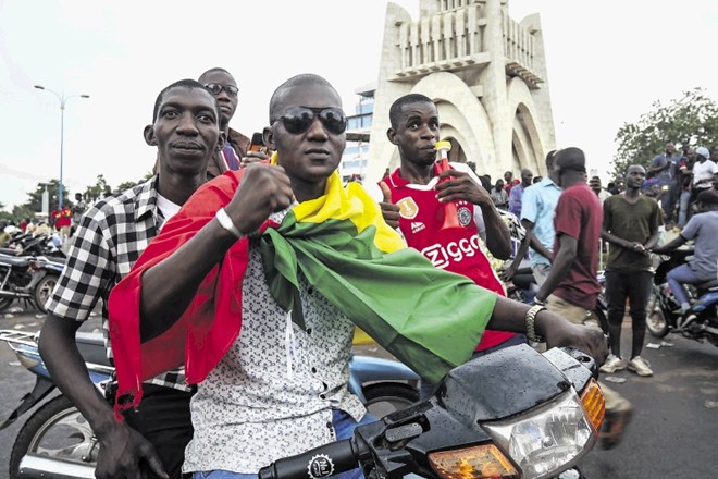 Moški, ovit v nacionalno zastavo, s someščani v Bamaku proslavlja odstavitev predsednika Ibrahima Keita, ki  so jo izvedli...