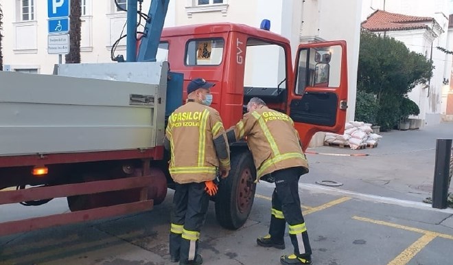 Prostovoljni gasilci iz Izole so včeraj prebivalcem razdelili nekaj protipoplavnih vreč.