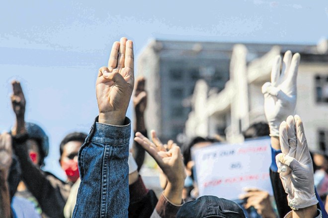Protestniki proti vojaški hunti protestirajo z visoko dvignjenimi tremi prsti, simbolom upora.