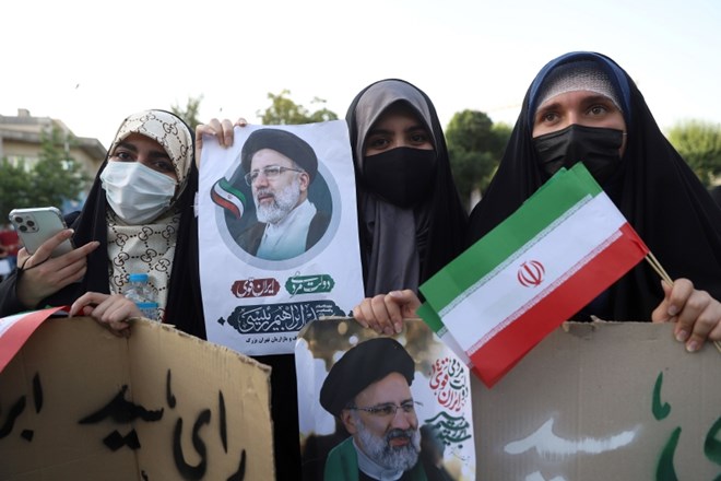 Podpornice Ebrahima Raisija držijo njegovo sliko na shodu v Teheranu.