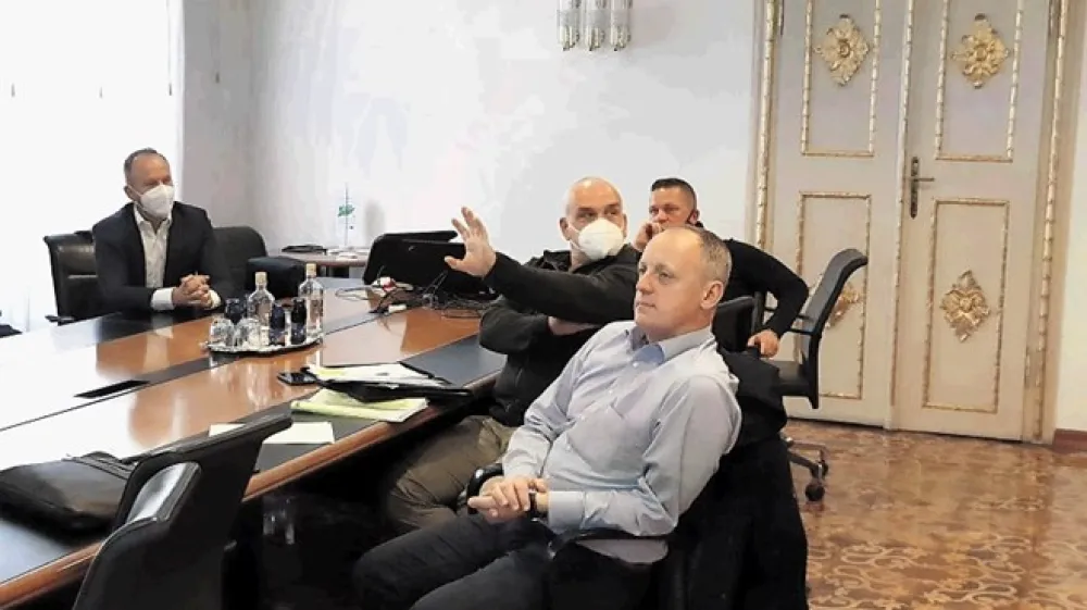 Na predstavitvi sistema Oko sokolovo sta bila tudi načelnik oddelka za gospodarske dejavnosti in promet David Polutnik (na fotografiji brez maske) in vodja mestnega redarstva Roman Fortuna (z masko). Polutnik nam je pojasnil, da je masko na sestanku odložil za kratek čas zaradi lažjega sporazumevanja in da je bila med udeleženci srečanja ves čas zagotovljena zadostna razdalja. Fotografije sicer govorijo drugače, saj udeleženci sestanka niso sedeli meter in pol narazen.
