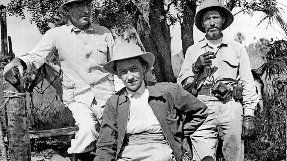 Branislava Su&scaron;nik (v sredini) se je na raziskovalnih odpravah pogosto oblačila v terenske uniforme, kakr&scaron;ne so imeli tudi angle&scaron;ki antropologi, s klobukom in &scaron;kornji vred; del obvezne opreme je bila tudi cigareta.