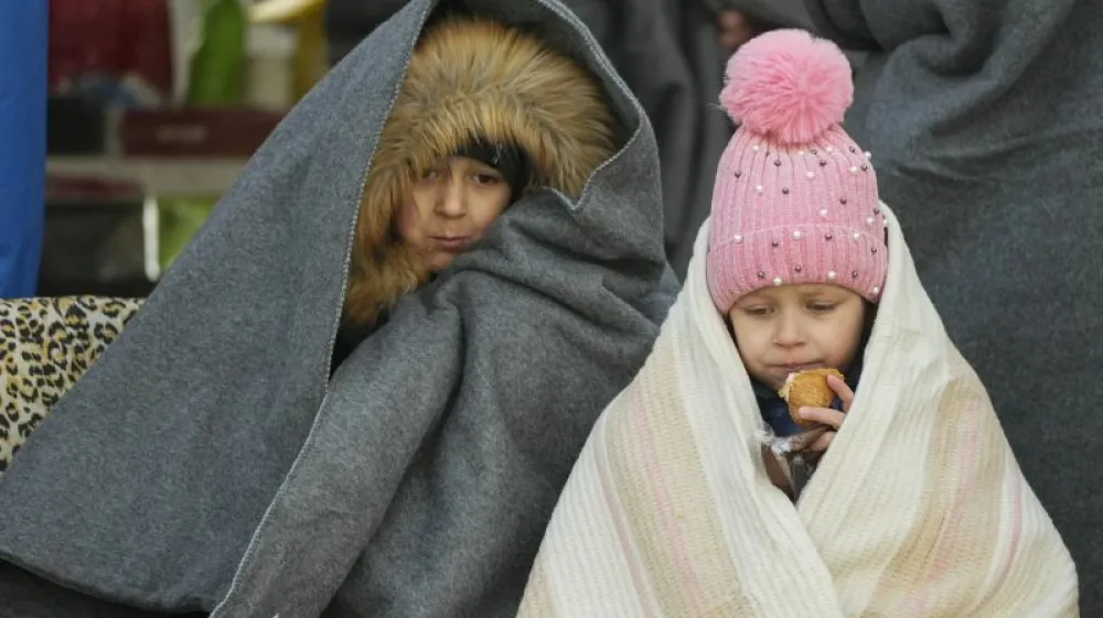 Ukrainian children covered themselves by blankets have a meal after fleeing the war from neighbouring Ukraine, at the border crossing in Palanca, Moldova, Thursday, March 10, 2022. (AP Photo/Pavel Golovkin)