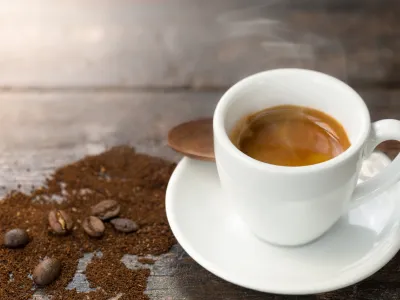 Espresso and coffee beans. Cup of hot espresso on wooden table with smoke.