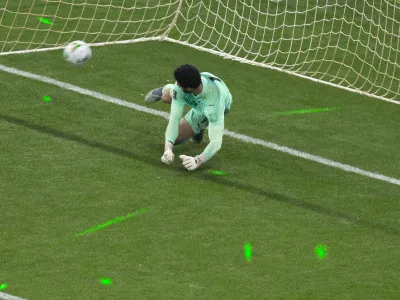 The light from green laser pointers can be seen on the pitch AS Egypt's goalkeeper Mohamed El-Shennawy fails to stop a shot during a penalty shootout at the end of the World Cup 2022 - Africa playoff soccer match between Senegal and Egypt at at Stade Me Abdoulaye Wade stadium in Dakar, Senegal, Tuesday, March 29, 2022. (AP Photo/Stefan Kleinowitz)