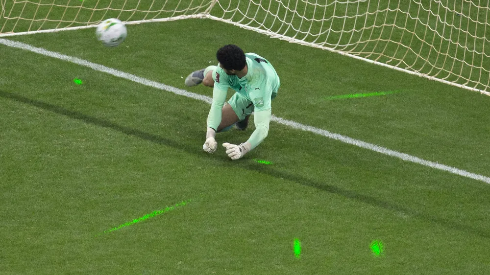 The light from green laser pointers can be seen on the pitch AS Egypt's goalkeeper Mohamed El-Shennawy fails to stop a shot during a penalty shootout at the end of the World Cup 2022 - Africa playoff soccer match between Senegal and Egypt at at Stade Me Abdoulaye Wade stadium in Dakar, Senegal, Tuesday, March 29, 2022. (AP Photo/Stefan Kleinowitz)