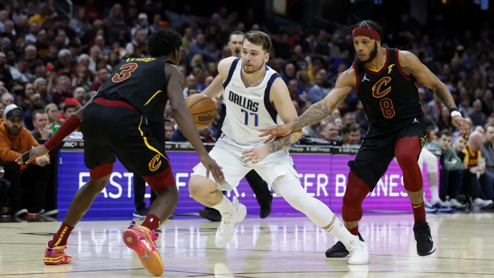 Dallas Mavericks guard Luka Doncic (77) drives against Cleveland Cavaliers forward Lamar Stevens (8) and guard Caris LeVert (3) during the second half of an NBA basketball game Wednesday, March 30, 2022, in Cleveland. (AP Photo/Ron Schwane)
