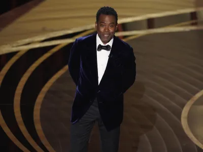 Chris Rock presents the award for best documentary feature at the Oscars on Sunday, March 27, 2022, at the Dolby Theatre in Los Angeles. (AP Photo/Chris Pizzello)