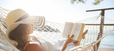 Woman in a hammock with book on summer day