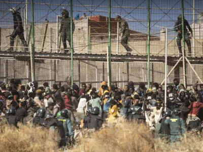 Riot police officers cordon off the area after migrants arrive on Spanish soil and crossing the fences separating the Spanish enclave of Melilla from Morocco in Melilla, Spain, Friday, June 24, 2022. Dozens of migrants stormed the border crossing between Morocco and the Spanish enclave city of Melilla on Friday in what is the first such incursion since Spain and Morocco mended diplomatic relations last month. (AP Photo/Javier Bernardo)