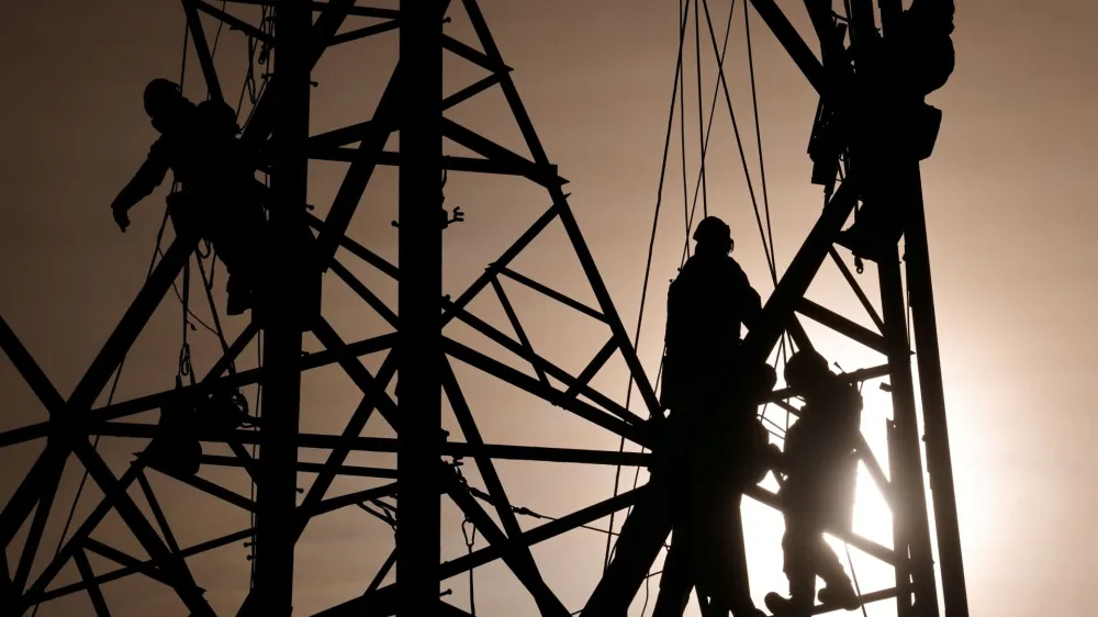 FILE PHOTO: Technicians work on an electricity pylon as part of the maintenance of high-tension electricity power lines in Bourbourg, France, February 18, 2021. REUTERS/Pascal Rossignol/File Photo
