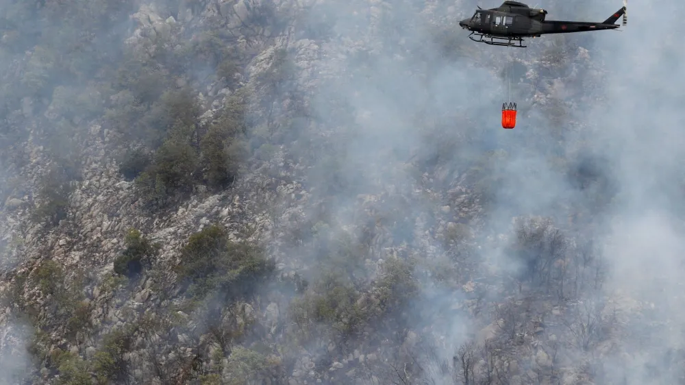 A Montenegrin army helicopter helps to extinguish a forest fire, during a heatwave, over the touristic area of Boka Bay in the city of Perast, Montenegro, August 10, 2022. REUTERS/Stevo Vasiljevic MONTENEGRO OUT. NO COMMERCIAL OR EDITORIAL SALES IN MONTENEGRO
