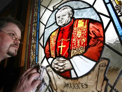 Parish priest Guenter Christoph Haase cleans the new church window showing a portrait of former Pope John Paul II, by Polish artist Monika Klas, at St. Nicholas Cathedral in Heuthen, eastern Germany, Wednesday, Dec. 7, 2005. It is one of the first church windows in Germany with a Pope John Paul II portrait. (AP Photo/Jens Meyer)