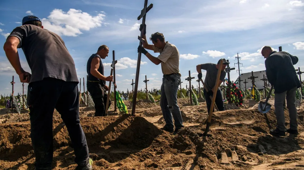 FILE PHOTO: A volunteer places a cross onto a grave of one of fifteen unidentified people killed by Russian troops, amid Russia's attack on Ukraine continues, during a burial ceremony in the town of Bucha, in Kyiv region, Ukraine September 2, 2022. REUTERS/Vladyslav Musiienko/File Photo