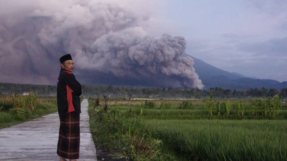 A man looks on as Mount Semeru releases volcanic materials during an eruption on Sunday, Dec. 4, 2022 in Lumajang, East java, Indonesia. Indonesia's highest volcano on the country's most densely populated island of Java erupted Sunday. (AP Photo)