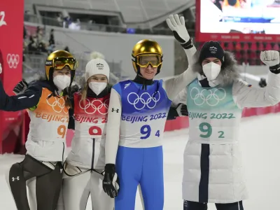 Slovenia's Ursa Bogataj, left, Nika Kriznar, second from left, Peter Prevc, second from right, and Timi Zajc celebrates after winning gold in the ski jumping mixed team event at the 2022 Winter Olympics, Monday, Feb. 7, 2022, in Zhangjiakou, China. (AP Photo/Matthias Schrader)