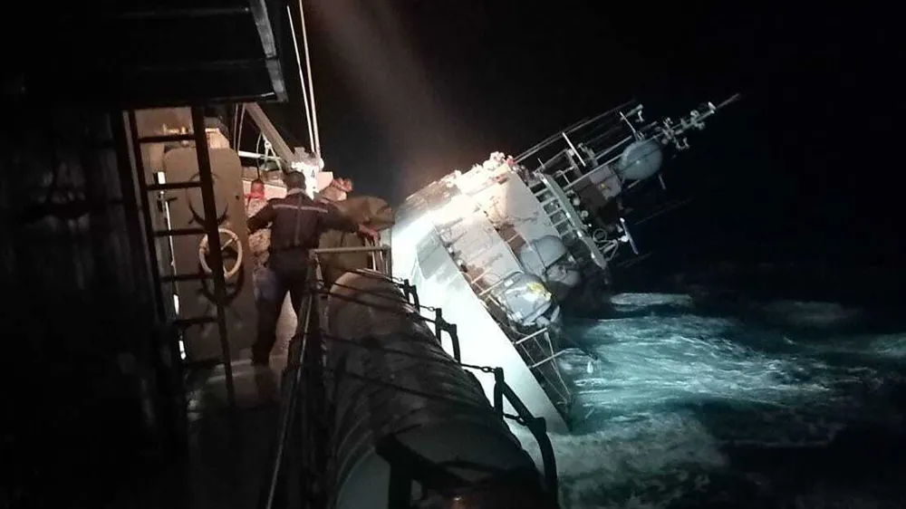 In this photo provided by the Royal Thai Navy, the HTMS Sukhothai corvette warship lists off the coast of Prachuap Khiri Khan province, Thailand, Sunday, Dec. 18, 2022. The Thai navy ship sunk in the Gulf of Thailand and ships and helicopters were working Monday to rescue sailors from the water. (Royal Thai Navy via AP)