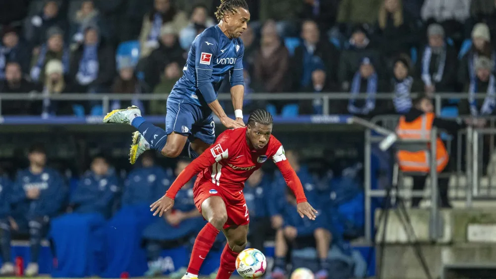 Bochum's Pierre Kunde, left, and Berlin's Jessic Ngankam challenge for the ball during the German Bundesliga soccer match between VfL Bochum and Hertha BSC Berlin in Bochum, Germany, Saturday, Jan. 21, 2023. (David Inderlied/dpa via AP)