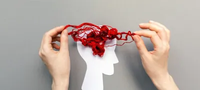 Tangled red threads on the silhouette of the head, representing the brain. Blue background. Flat lay. The concept of mental health and demension