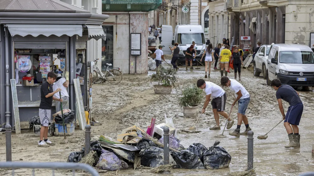 People remove mud from a street in Senigallia, central Italy, Friday Sept. 16, 2022. Flash floods triggered by heavy rain have swept through towns in a hilly central Italy. &nbsp;Italy's leader Mario Draghi said 10 people were dead in the floods and four were missing. (Guido Calamosca/LaPresse via AP)