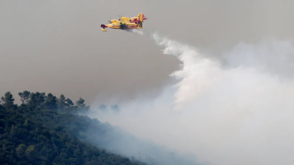 Smoke fills the sky as a Canadair firefighting plane releases water to extinguish a wildfire near Seillons, in the Var department, France, July 25, 2017. REUTERS/Jean-Paul Pelissier