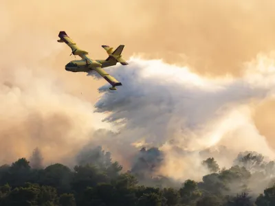 A firefighting plane sprays water to extinguish wildfire at Ciovo island, Croatia, Thursday, July 27, 2023. A large fire is reported on the island of Ciovo, close to Split on the Croatian Adriatic coast. (AP Photo/Miroslav Lelas)