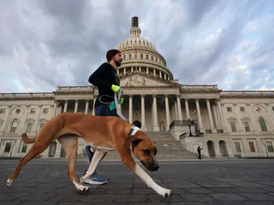 A man jogs with his dog past the U.S. Capitol on a day where Republican members of the House will continue to work towards electing a new Speaker of the House in Washington, U.S., October 10, 2023. REUTERS/Kevin Lamarque