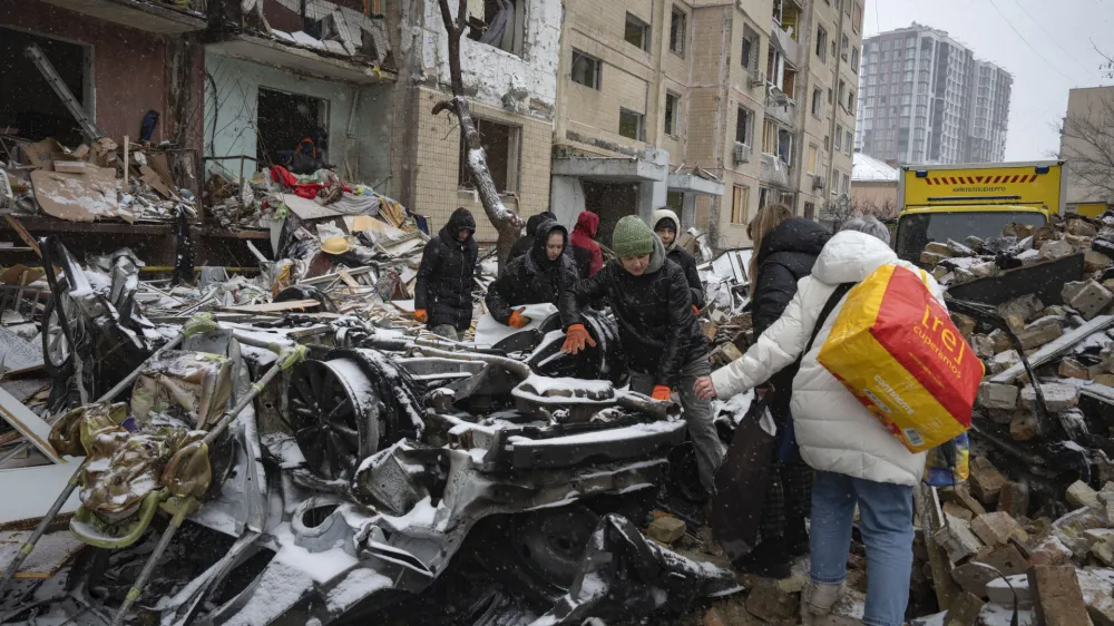 Volunteers and residents clear debris of an apartment building destroyed after Russian attack in Kyiv, Ukraine, Wednesday, Jan. 3, 2024. (AP Photo/Efrem Lukatsky)